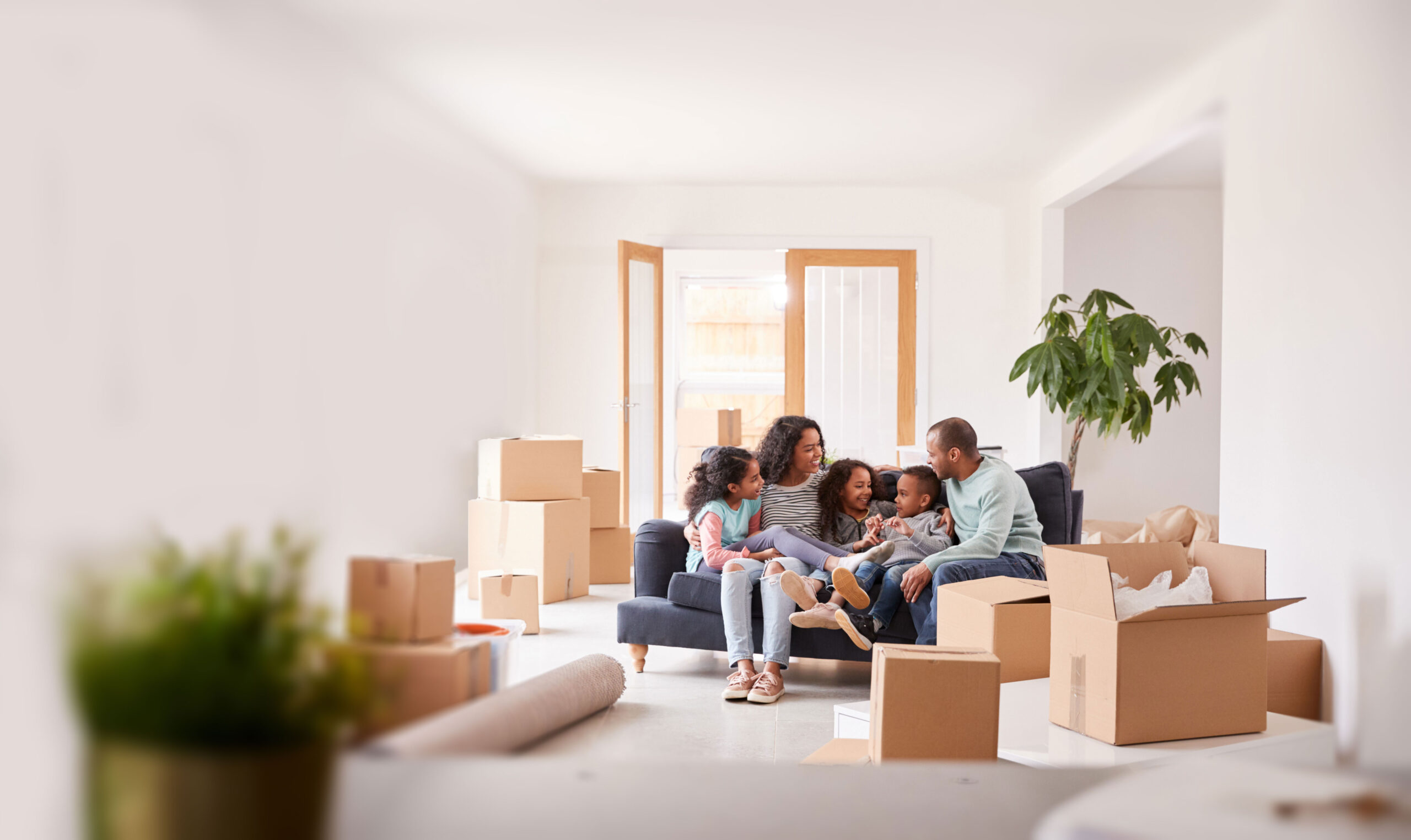 Akron Movers unloading furniture and boxes into a home where a happy family is sitting.