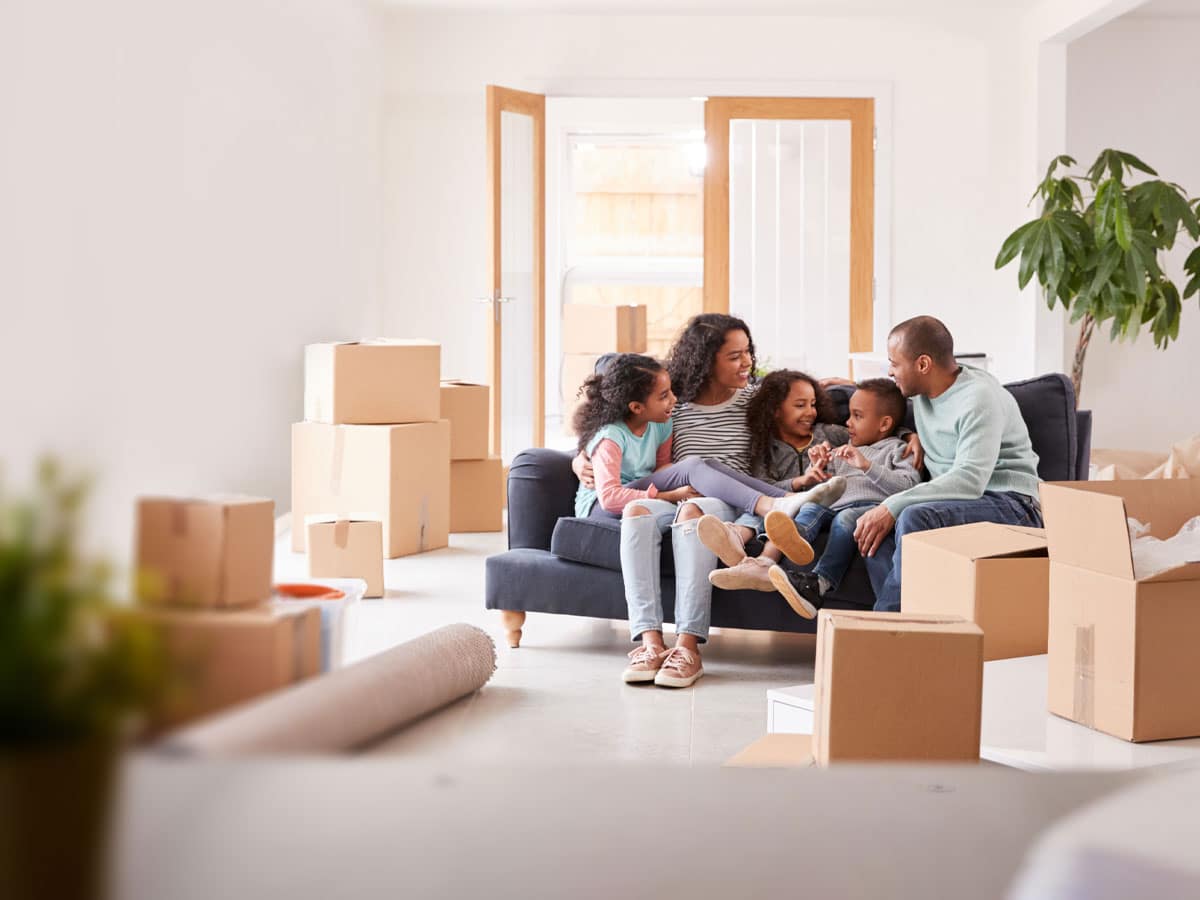 Akron Movers unloading furniture and boxes into a home where a happy family is sitting.